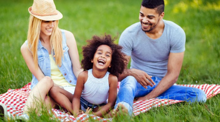 Couple with their daughter having picnic on a blanket
