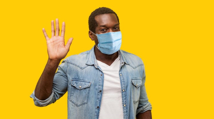 Man wearing a medical mask waving hello