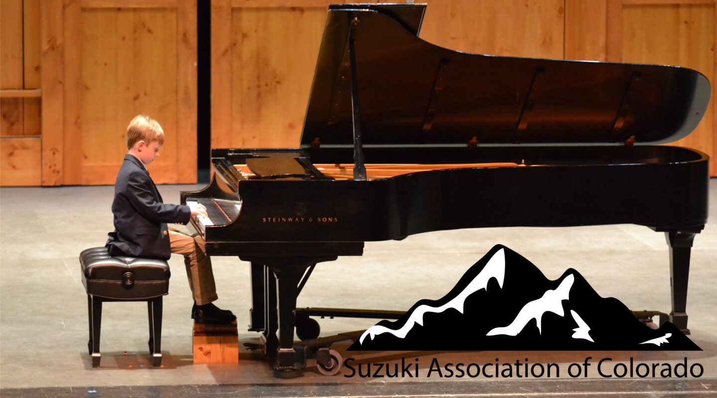 A young pianist from the Suzuki Association of Colorado plays the piano on a raised stage.