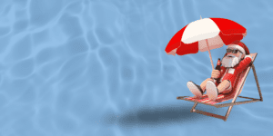 Santa Claus sunbathing under a red and white umbrella